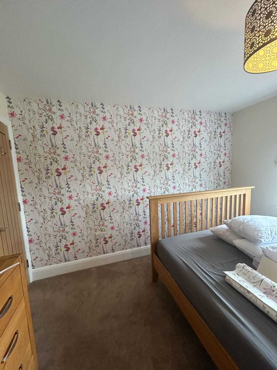 Floral feature wall wallpaper in a bedroom with painted walls either side