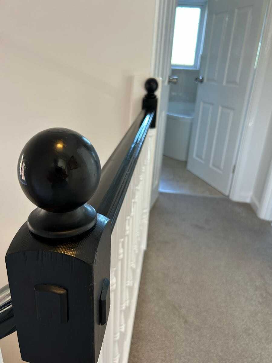 Gloss black painted staircase newel post with white spindles