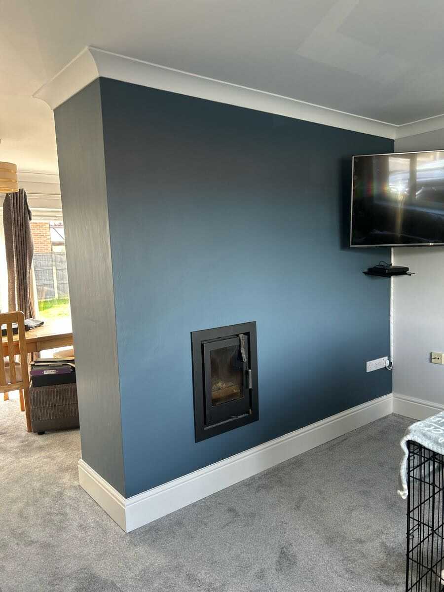 Deep teal feature wall with log burner surround in a living room