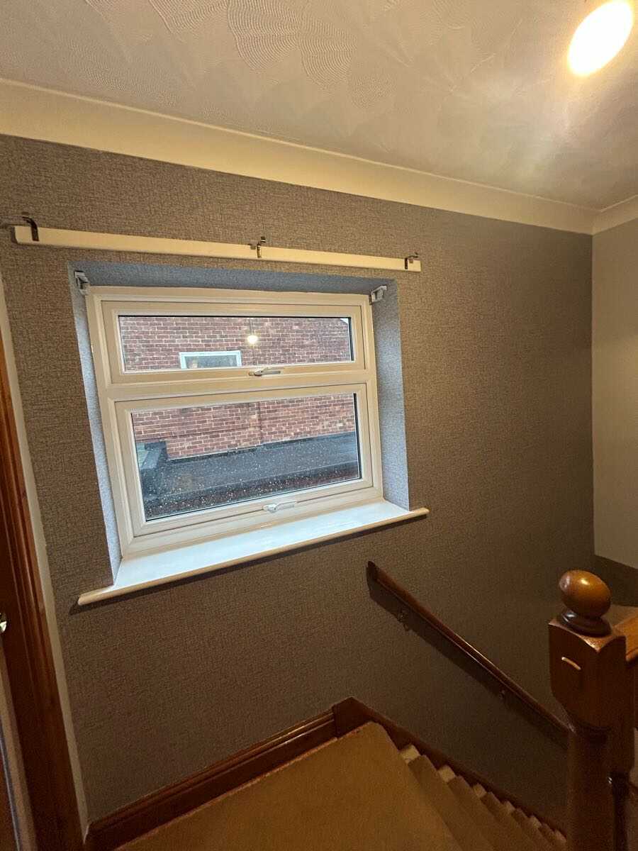 Textured wallpaper hung on staircase wall with cream painted woodwork
