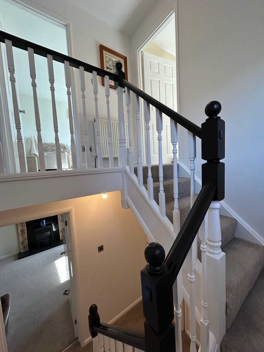 Full staircase with black painted handrail and newel posts and white spindles